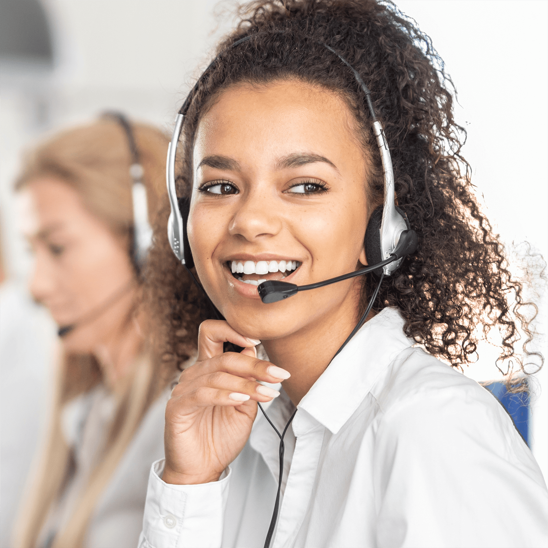 A smiling customer service representative wearing a headset in an office setting.