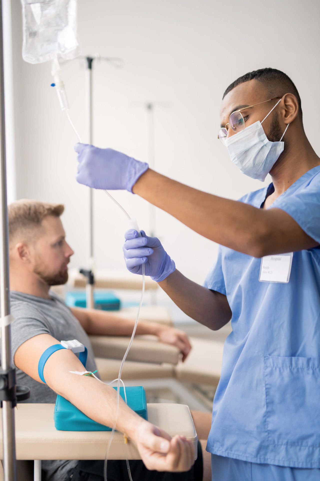 A healthcare worker in a mask and gloves administers a vaccine to a patient seated in a clinical setting.