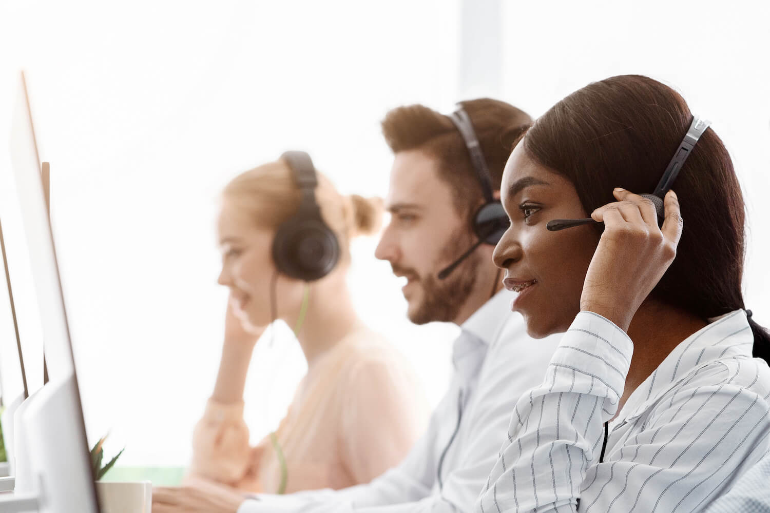 Focused customer service representatives wearing headsets are working at their computers.